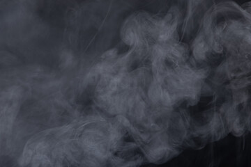 Dense Fluffy Puffs of White Smoke and Fog on black Background, Abstract Smoke Clouds, Movement Blurred out of focus. Smoking blows from machine dry ice fly fluttering in Air, effect texture