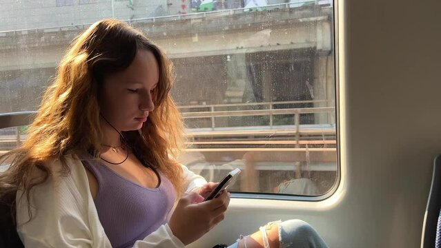 Vancouver Canada a girl is sitting near the window of the skytrain no one is visible near her only blue empty seats She is looking at the social network on the phone she is busy Travel trips migrants