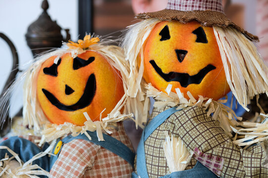 two pumpkin head scarecrow on display next to a babys portrait