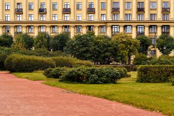 Facade of a retro residential building with columns, next to the park. Vintage building with windows and balconies.