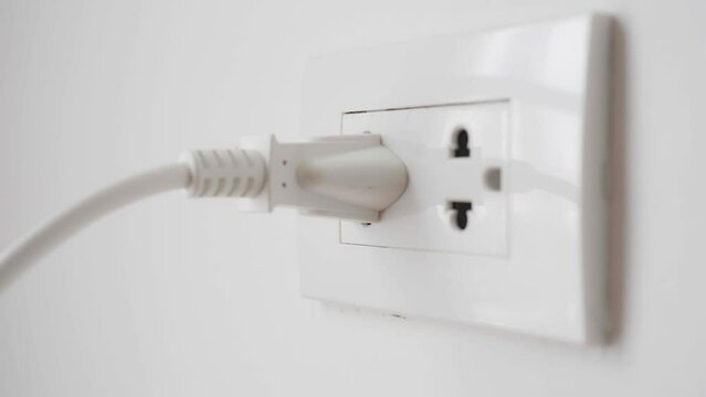 Close up of hand plugging in power cord and unplugging into socket to save energy, Reduce energy efficiency