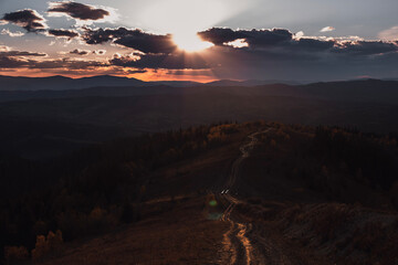 Sunset in the mountains. Autumn landscape in the evening with long road. 