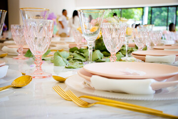 Cristalería y vajilla rosa con cubiertos dorados