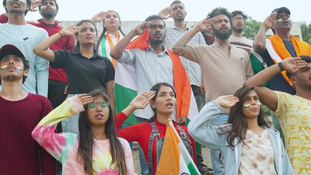 group of audience with Indian flag in hand and painted indian flag on face singing national anthem at stadium - concept of respect, patriotic and togetherness