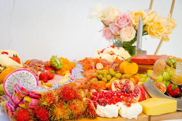 Tabla de quesos y carnes frías en evento con flores de fondo