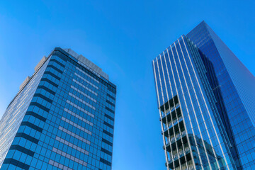 Facade of buildings with glass exterior towering against the clear blue sky