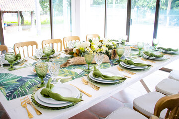 Mesa con decoración verde estilo tropical, servilletas verdes, cubiertos dorados 