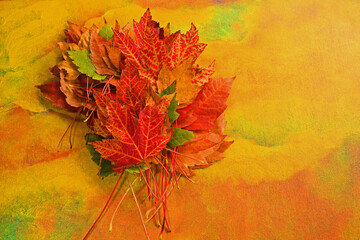 Many Autumn colored leaves bunched up and on Autumn colored background with copy space