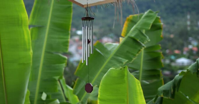 Wind Chimes hangs on the porch of the house against the backdrop of the tropical jungle and mountains