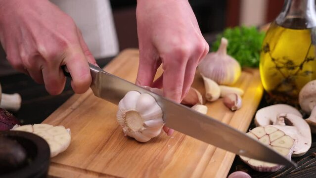woman slicing garlic on wooden cutting board at domestic kitchen