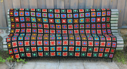 Homemade knitted old bedspread on a wooden bench