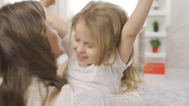 Child girl hugging her mother in slow motion.
Girl running to her mother at home hugging.
