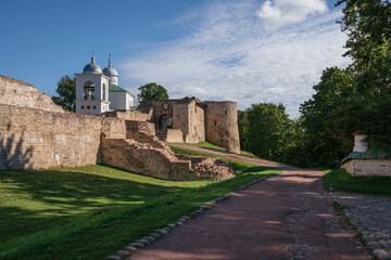 Fototapeta na wymiar View of the wall of the Izborsk fortress, the Nikolsky Gate and St. Nicholas (Nikolsky) Cathedral (XIV-XVII century) on a sunny summer day, Izborsk, Pskov region, Russia