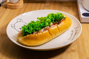 Hotdog with bacon and sausage on white plate