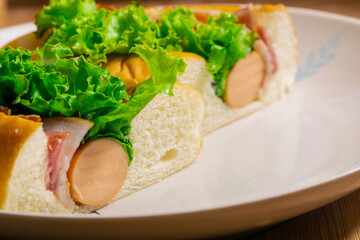 Hotdog with bacon and sausage on white plate
