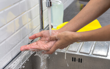 Hands washing with liquid soup and running water in kitchen sink, Hands concept