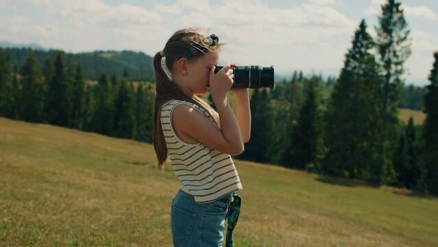 Young photographer shooting landscape on beautifull green hillway, taking pictures of nature. Girl filling the portfolio with amazing photos, spending leisure time outdoor. Slow motion.