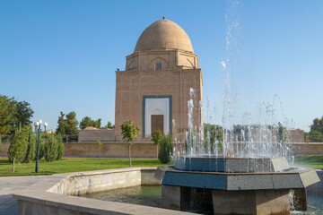 City fountain against the background of the medieval Rukhabod mausoleum on a sunny day. Samarkand,...