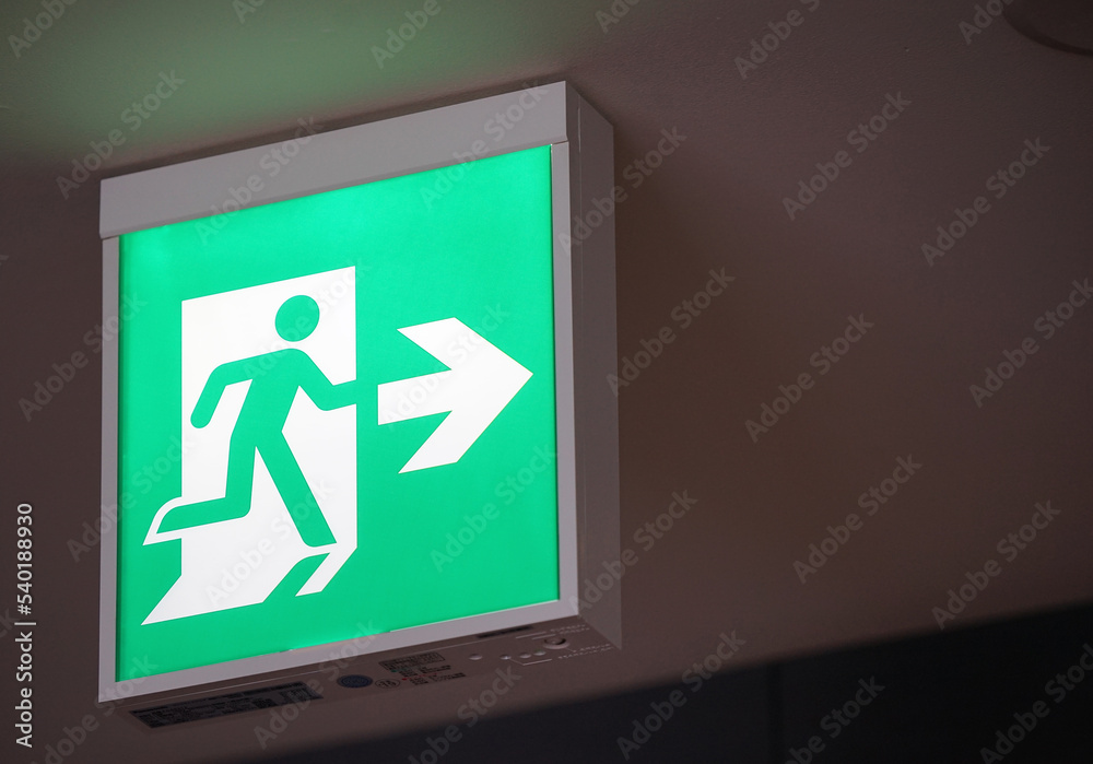 Wall mural glowing green emergency exit signs indoors in japanese buildings