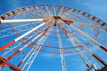 A large red and white Ferris Wheel against a blue sky