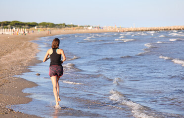 Fototapeta na wymiar athletic girl running on the beach by the sea to train