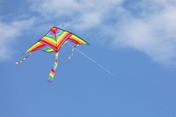 colorful kite with the multi colors of the rainbow flies free in the sky