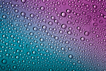 Water drops on glass as a background. Condensation on a cold drink. Multicolored background with drops texture.