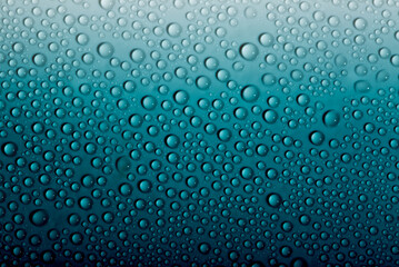 Water drops on glass as a background. Condensation on a cold drink. Blue background with drops texture.