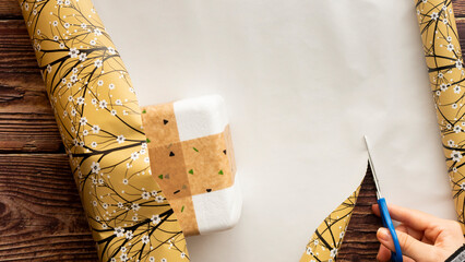 Girl wrapping a gift. Hands of a girl cutting the white flower paper to wrap the gift. Copy space