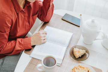 middle aged woman is sitting on a sofa in a room and reading book, life-long learning