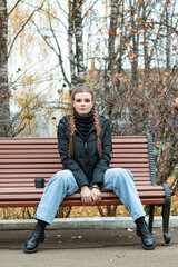 A young girl is sitting on a bench in a city park.