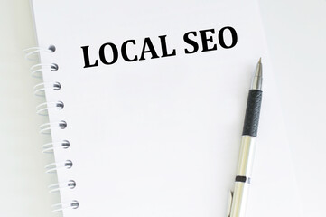 Text LOCAL SEO inscription on a white notepad, a pen lies on the table next to it. business, finance and development concept
