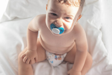 unhappy upset crying baby toddler infant toddler with pacifier in mouth sitting lying in baby crib.dissatisfied child crying ou nervous angry making whims air and graces.sunshine sunny rays morning