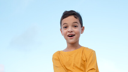 Cheerful positive child, blue sky on the background. Surprised face of a boy 8 years old. Emotion,...
