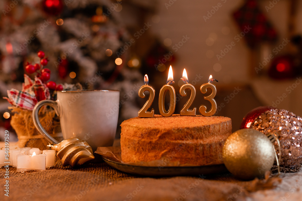 Wall mural homemade honey cake in the kitchen with candles 2023. Cozy New Year at home. Merry Christmas. High quality photo