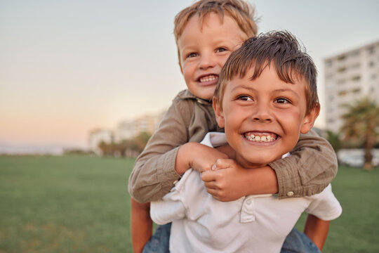 Happy, smile and portrait of brothers with piggyback ride playing in a park together on vacation. Happiness, excited and children bonding in nature while on a summer holiday adventure in Australia.
