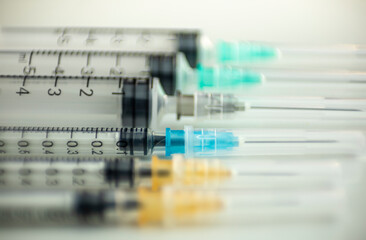 Six syringes of different thicknesses and colors on a well-lit white table