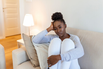 Sad african american woman with depression sitting on sofa. lonely stressed upset young black girl...
