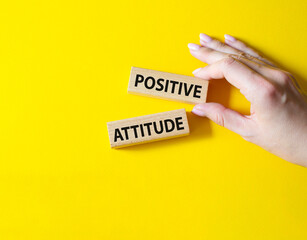 Positive attitude symbol. Concept words Positive attitude on wooden blocks. Beautiful yellow background. Businessman hand. Business and Positive attitude concept. Copy space.