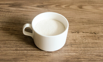 Obraz na płótnie Canvas White mug with sugar on a wooden table