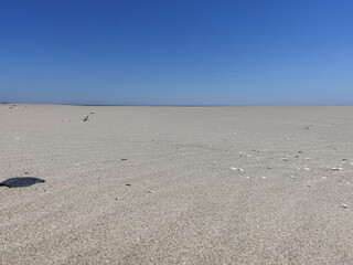 The light grey sand of a beach of Camargue with the sky in background blue azure.
