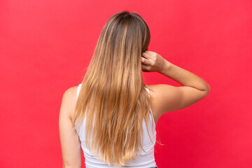Young beautiful woman isolated on red background in back position and thinking