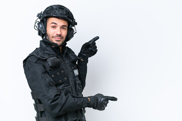 Fototapeta premium Young caucasian SWAT man isolated on white background pointing finger to the side and presenting a product