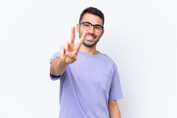 Young caucasian man isolated on white background smiling and showing victory sign