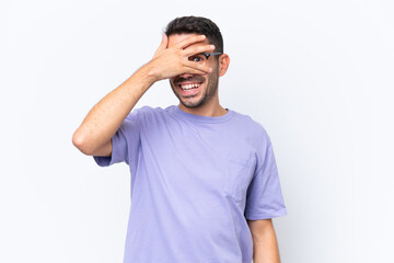 Young caucasian man isolated on white background covering eyes by hands and smiling