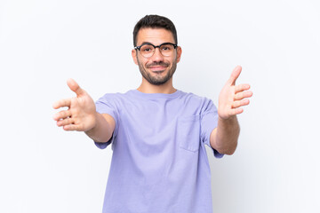 Naklejka premium Young caucasian man isolated on white background presenting and inviting to come with hand
