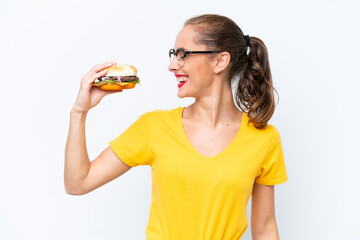 Young caucasian woman holding a burger isolated on white background looking side