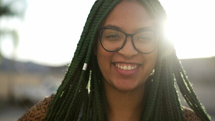 African American young woman. A black adult girl with braided hair smiling at camera outside in sunlight