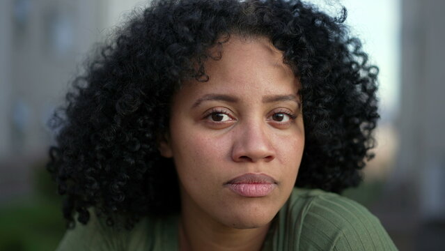 Portrait face of a young black woman looking at camera. A hispanic South American Brazilian adult girl with curly hair with natural expression