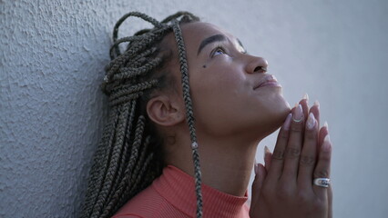 One spiritual young black woman praying to God pleading help and support. A faithful Brazilian...